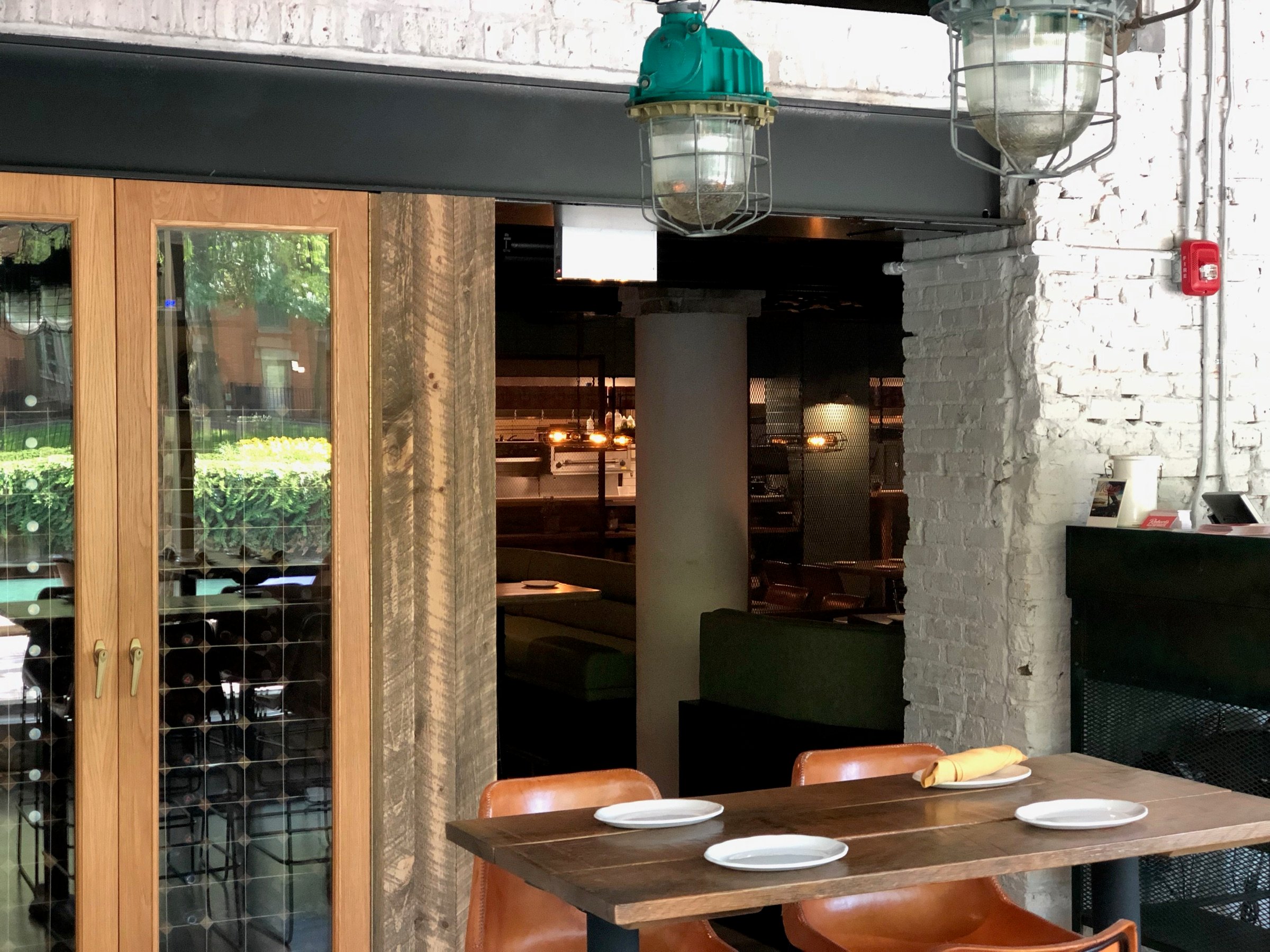 Wide view of Roberts Pizza's bar with custom shelving, warm wood, and industrial lighting