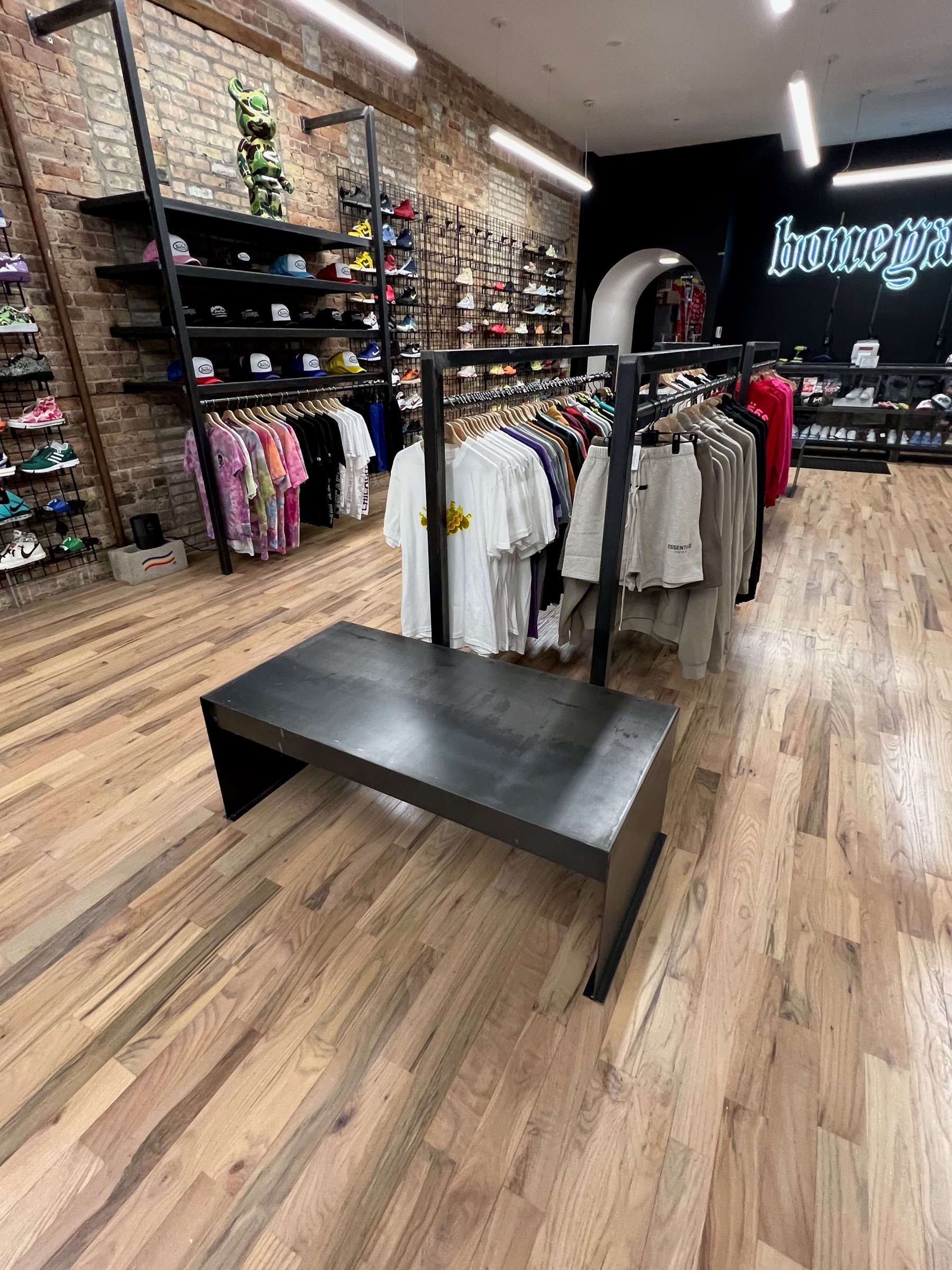 Custom black steel apparel fixtures along the dark side wall inside Boneyard