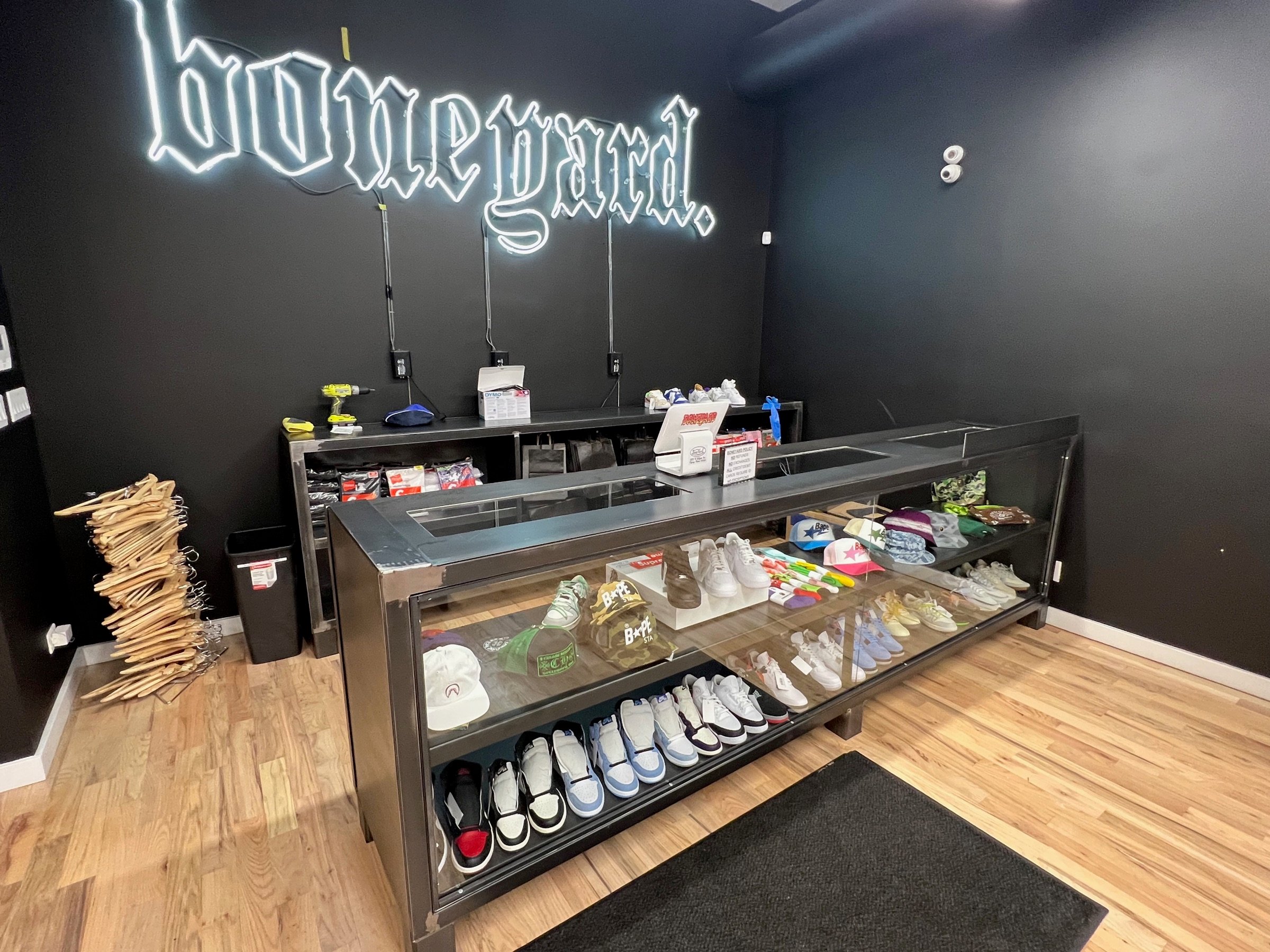 Checkout area with illuminated Boneyard signage and a glass sneaker display case
