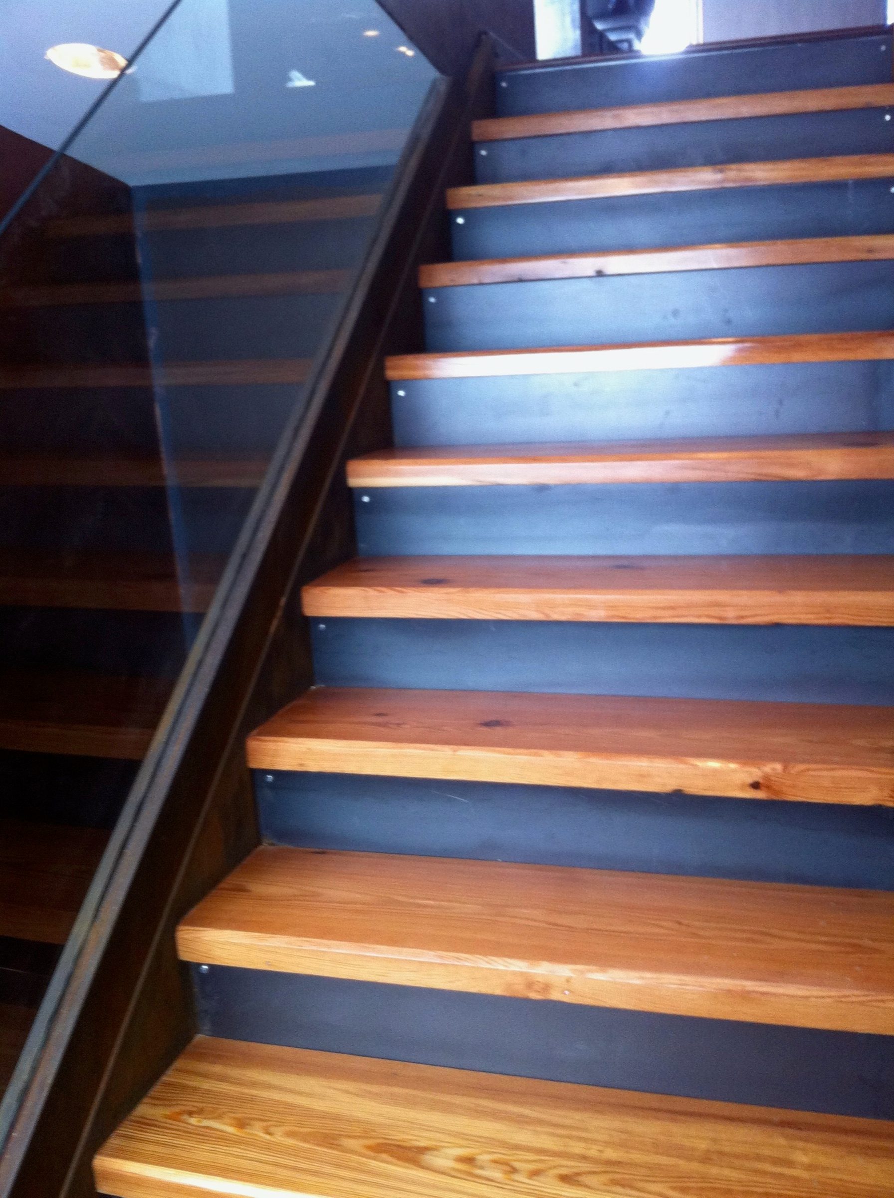 Finished steel stringer staircase with thick wood treads and a glass guard