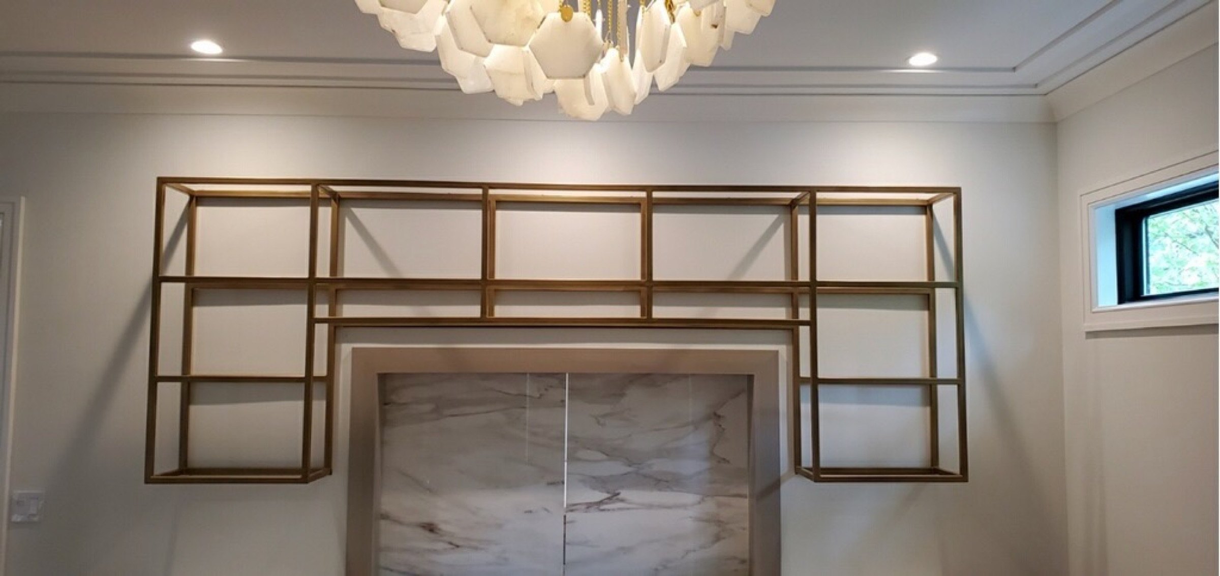Wide finished view of the gold-finished steel shelving installed above a marble-backed bar