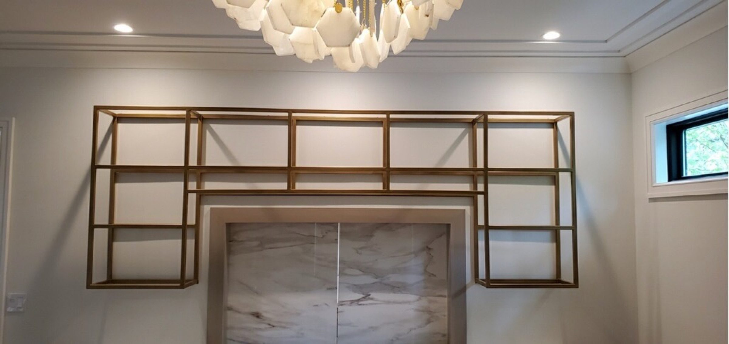Wide finished view of the gold-finished steel shelving installed above a marble-backed bar