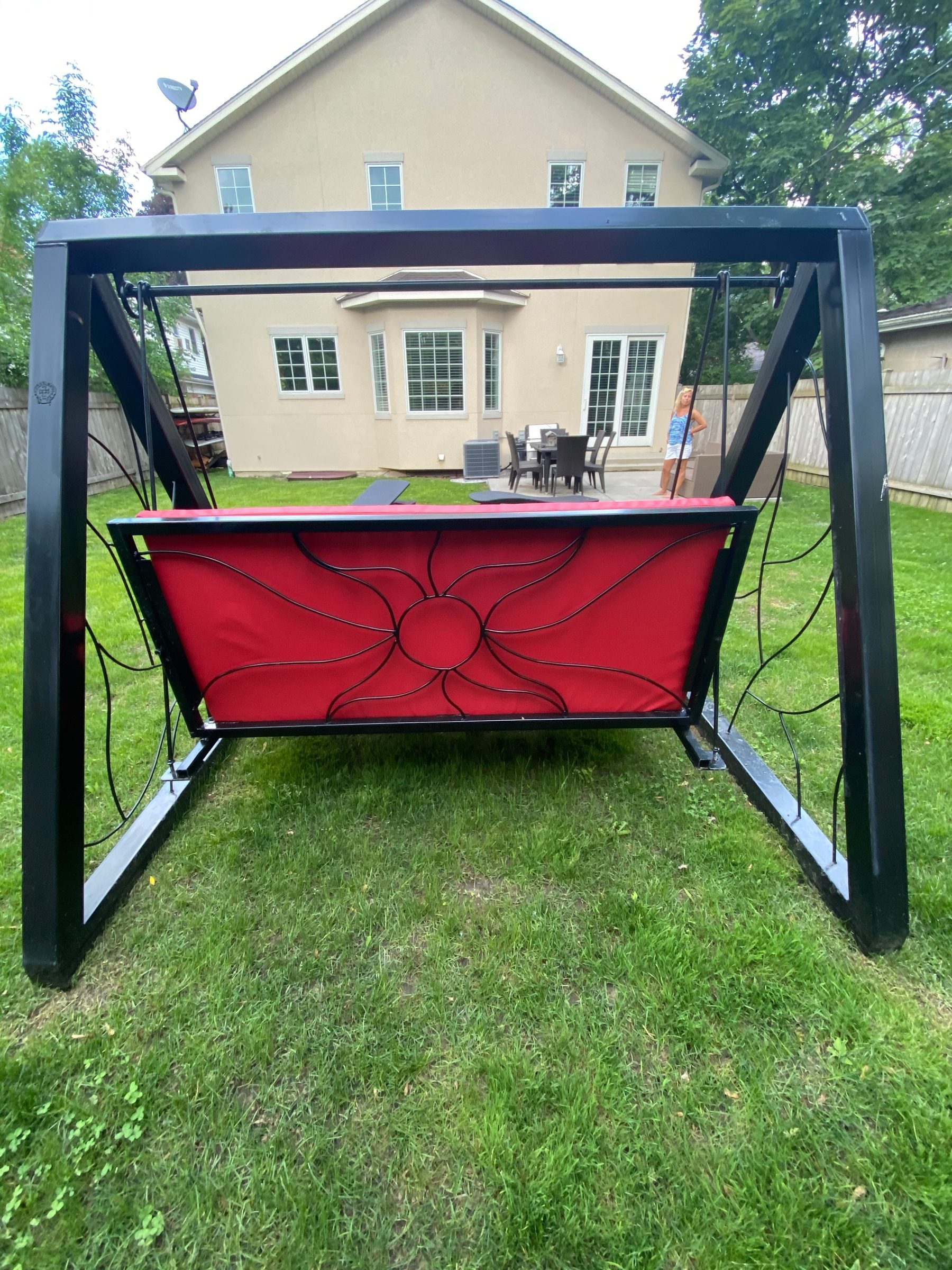 Red powder-coated porch swing with hand-forged floral iron panels