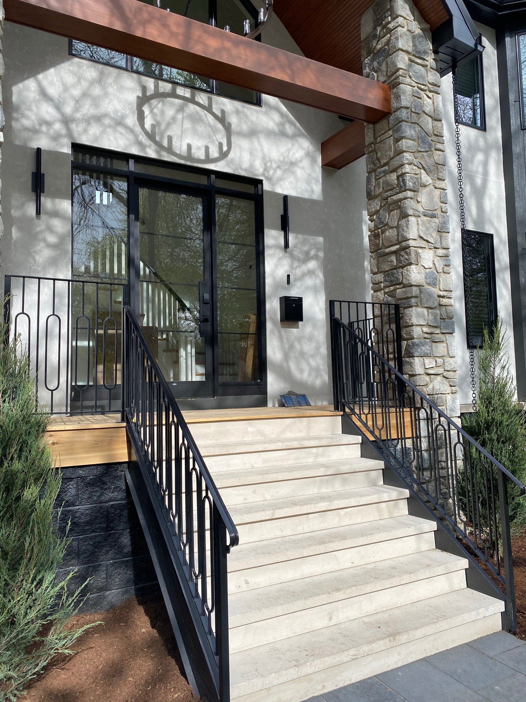 Dark geometric steel railing on a stone-column entrance