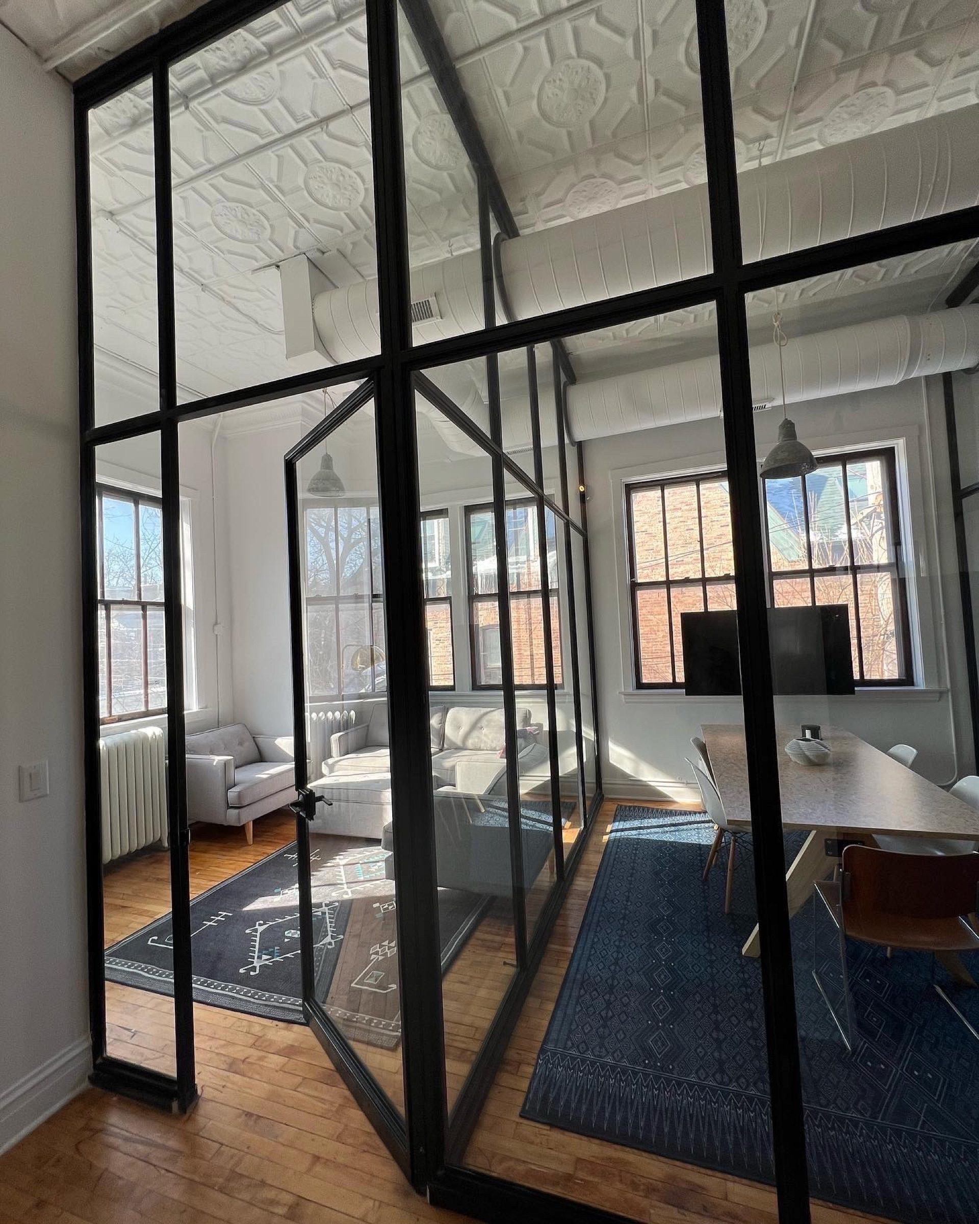 Steel-and-glass loft partition set below an ornamental tin ceiling
