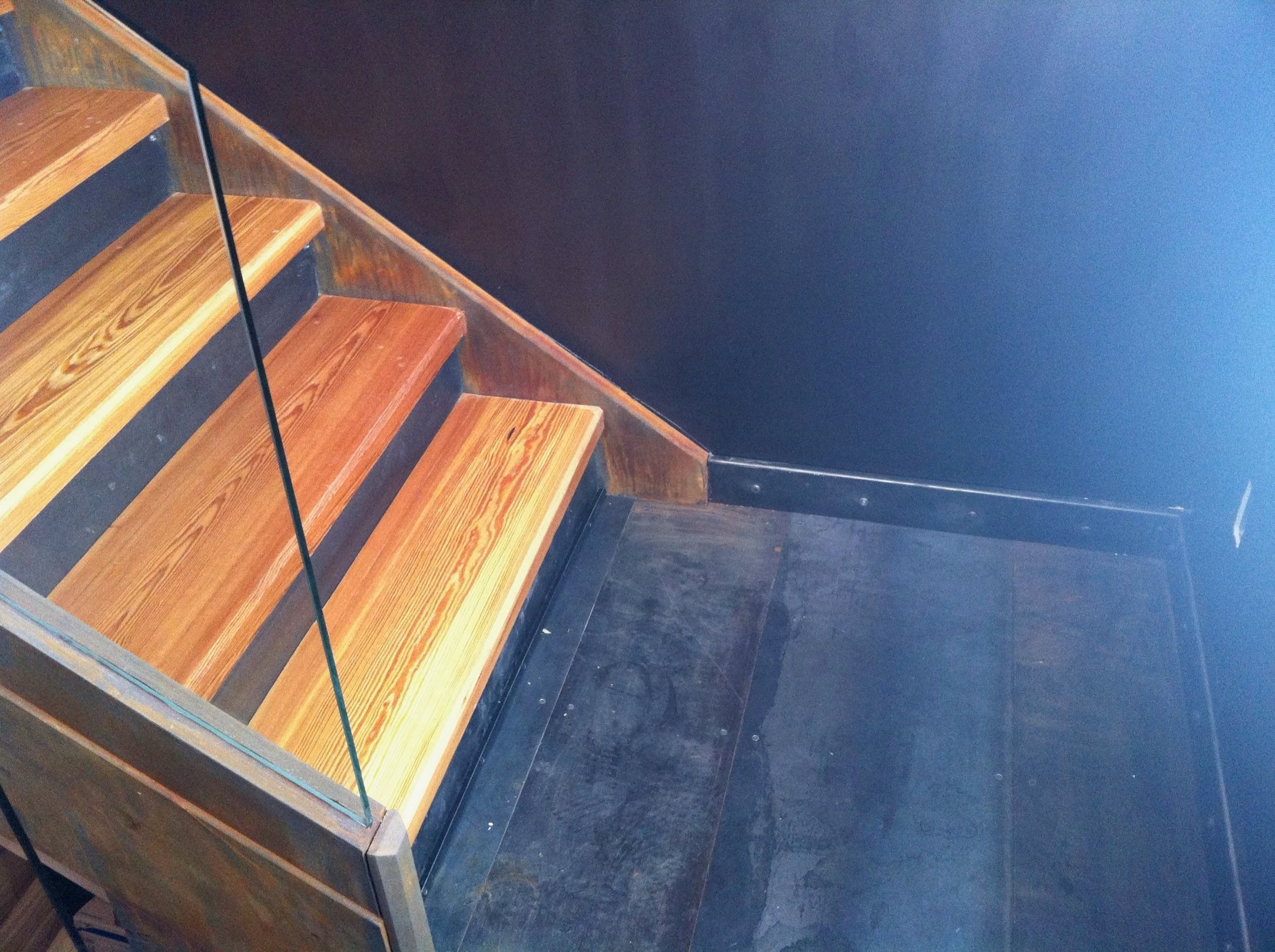 Landing detail of the steel stringer staircase with wood treads and glass guard
