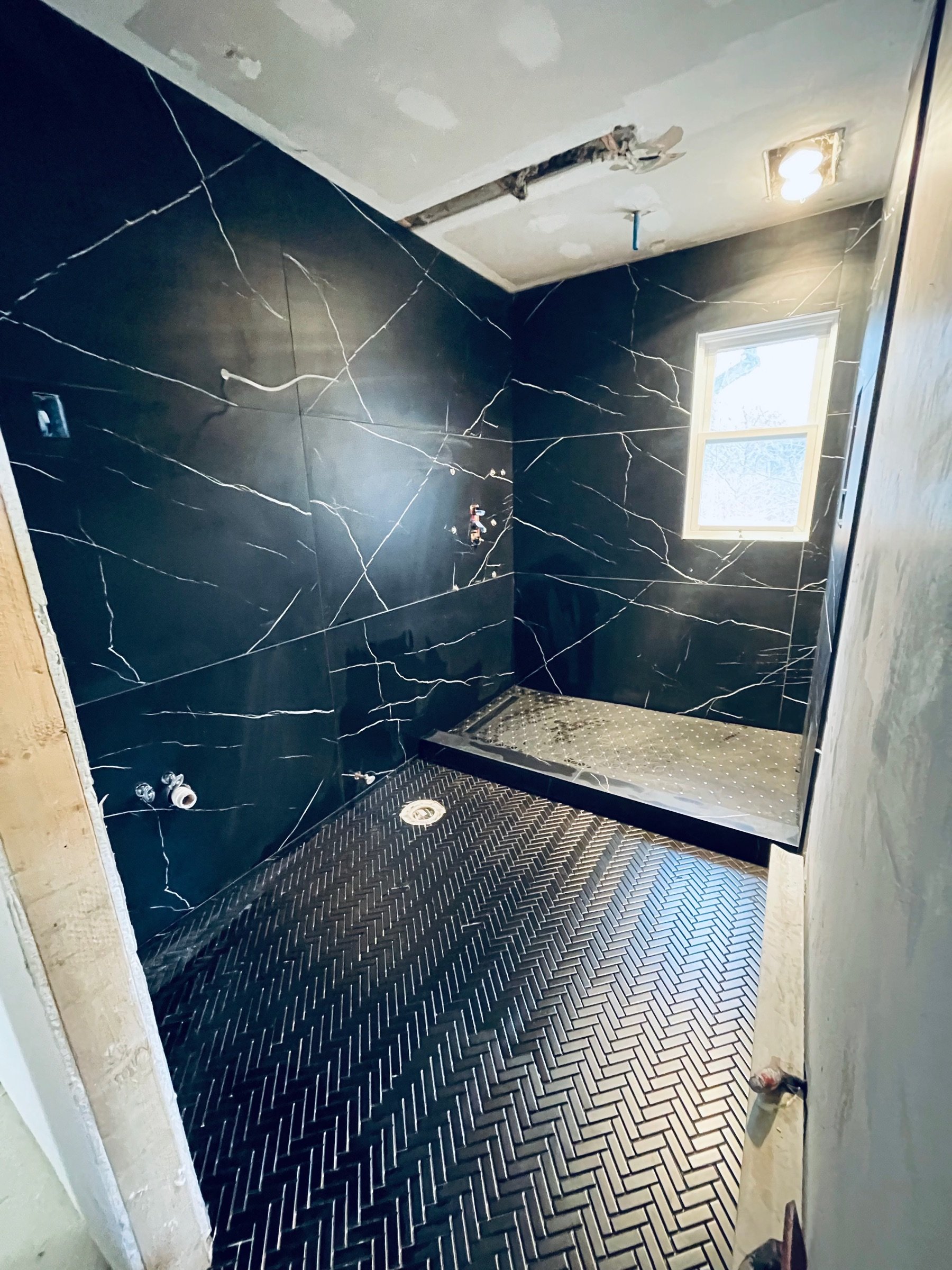Black marble bathroom with frameless glass shower at 880 Blue Star