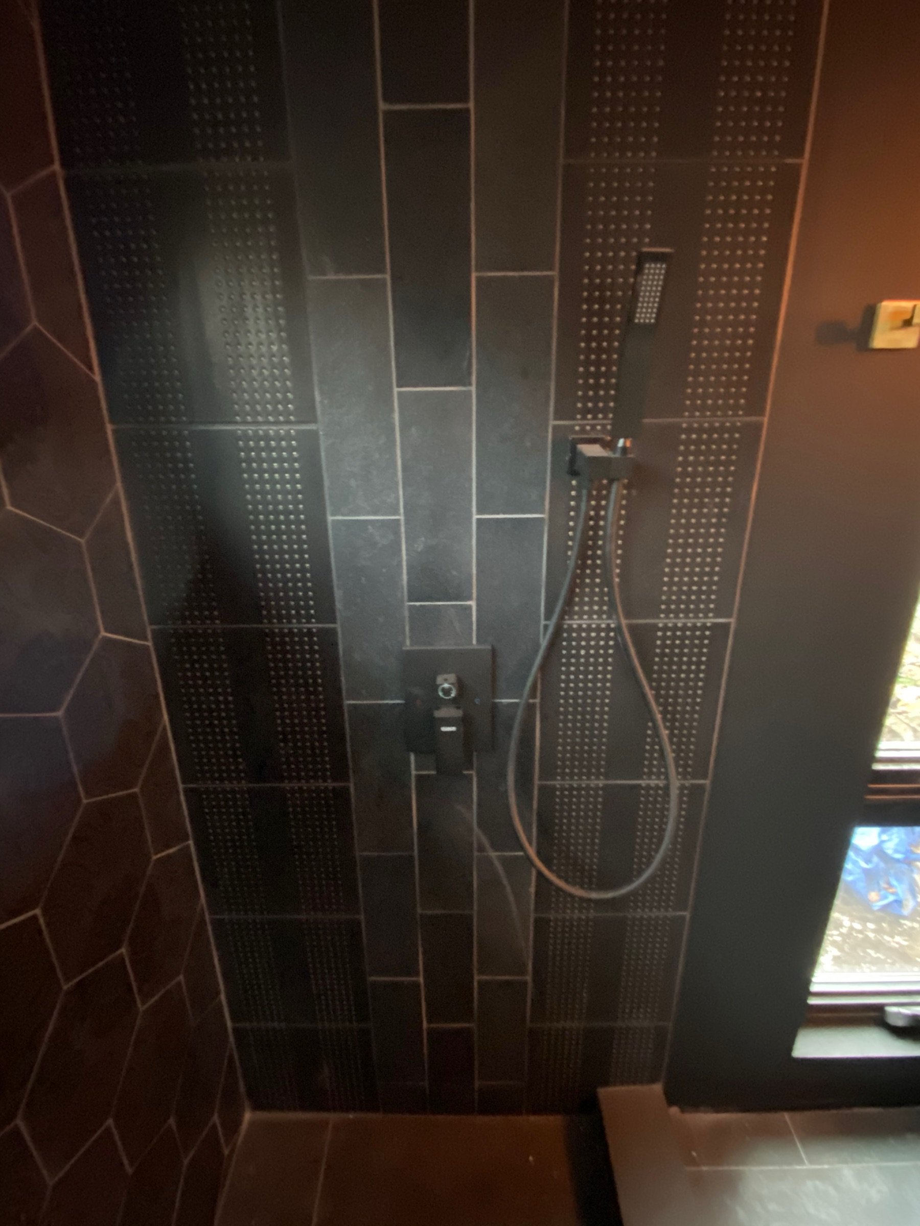Compact shower with dark tile and graphic finishes in the Mini House bath