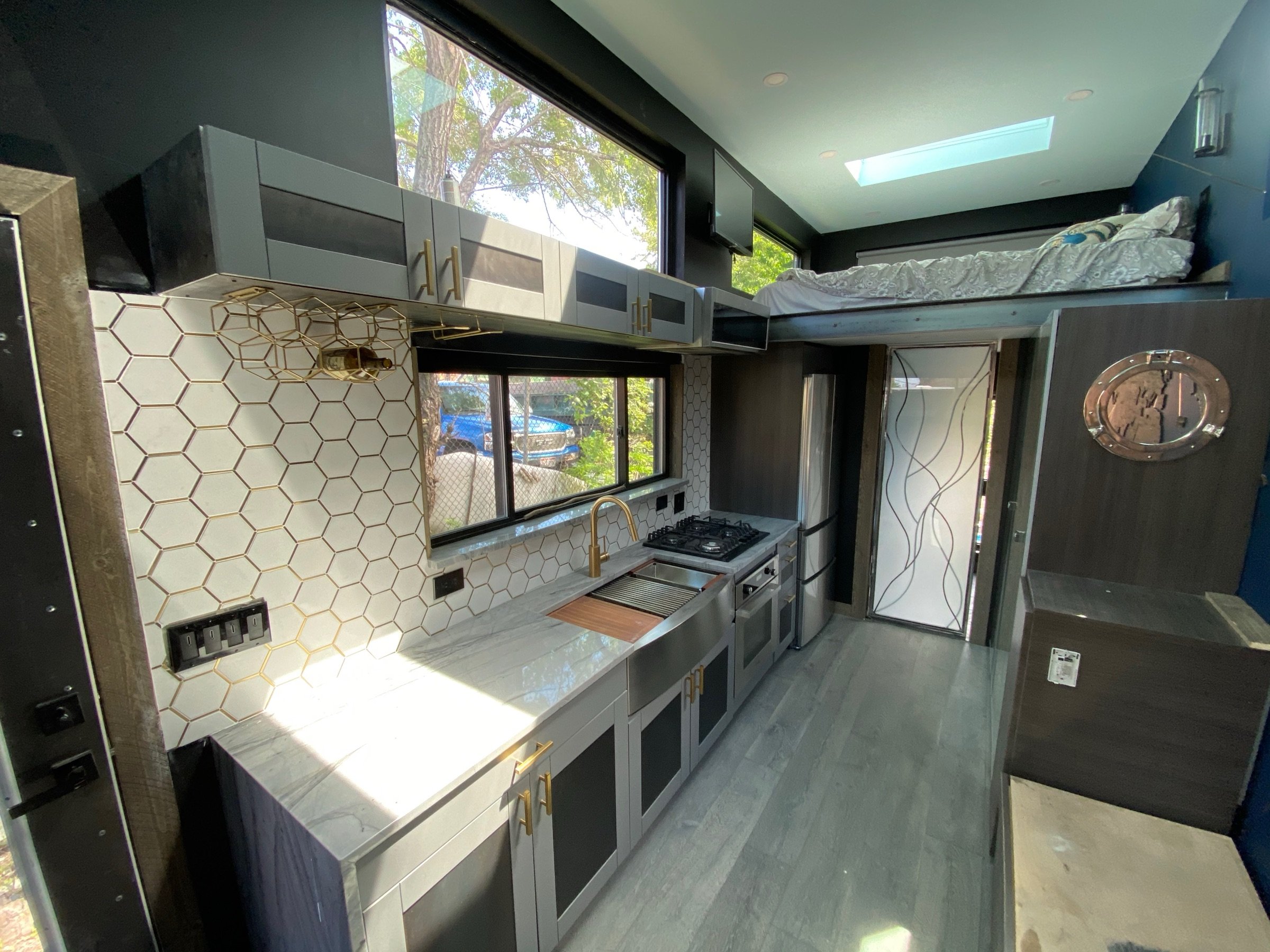 Custom kitchenette with integrated storage, brass hardware, and daylight from the side window