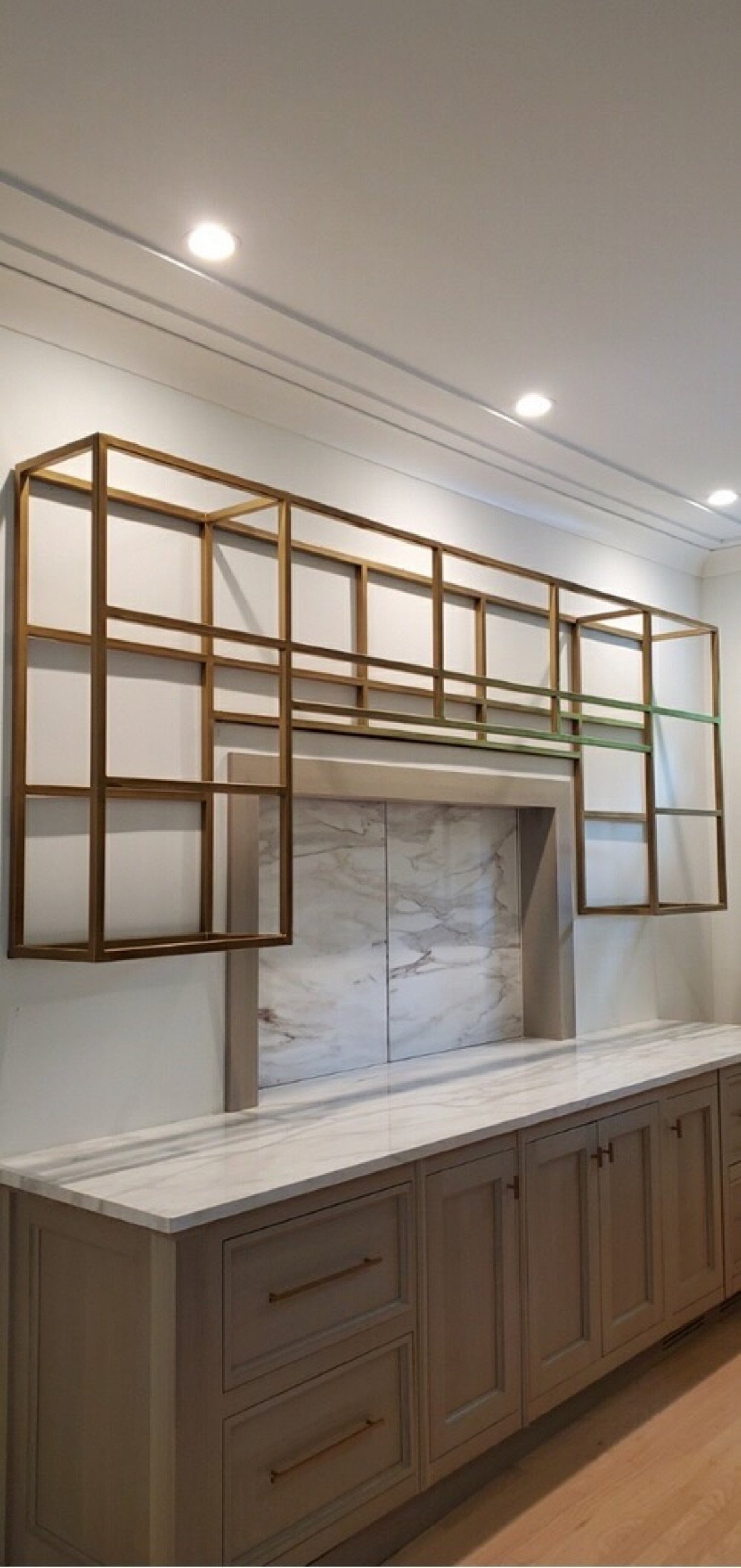 Front view of the finished gold-finished steel shelving and marble counter